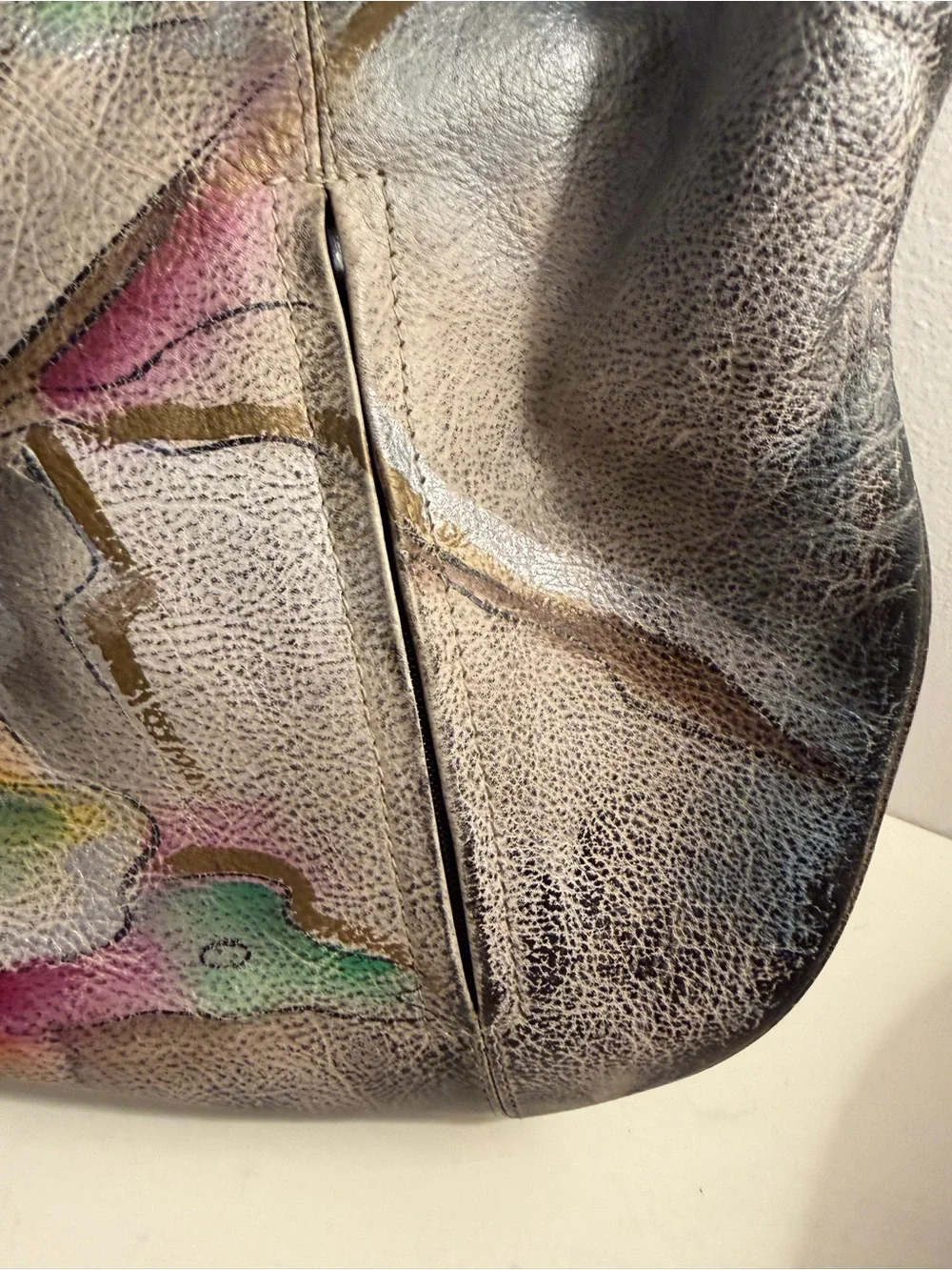 Distressed leather hobo bag with colorful abstract design on front and back.